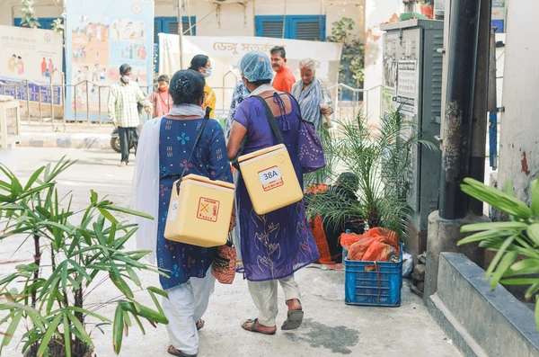 Healthcare workers carrying traditional cold boxes